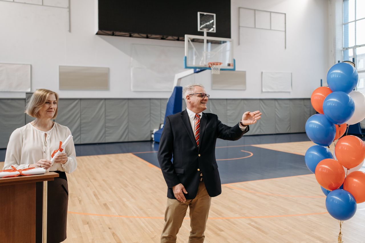 Crafting Captivating Headlines: Your awesome post title goes here School ceremony in a gymnasium with a teacher and official celebrating.